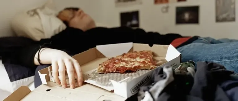 Boy sleeping with pizza on bed